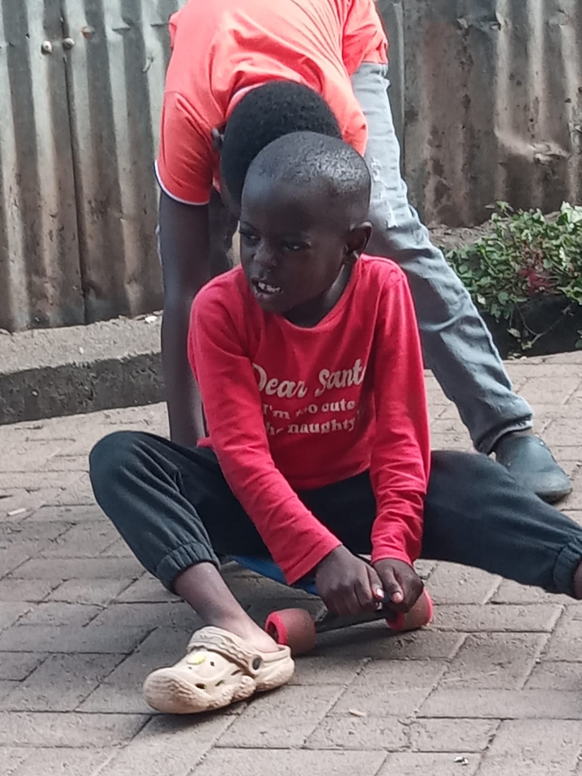 Young child seated on a skateboard being coached